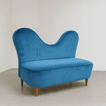 Divano di Cesare Lacca in velluto turchese esposto in galleria d’arte.