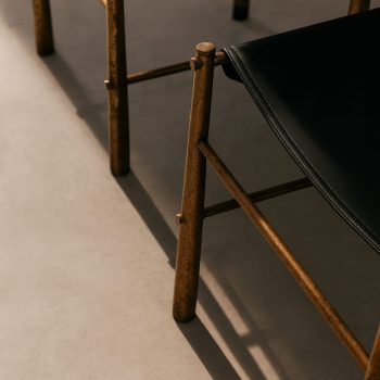 Detail of the patinated brass frame and black leather of the vintage Italian chair, 1970s.