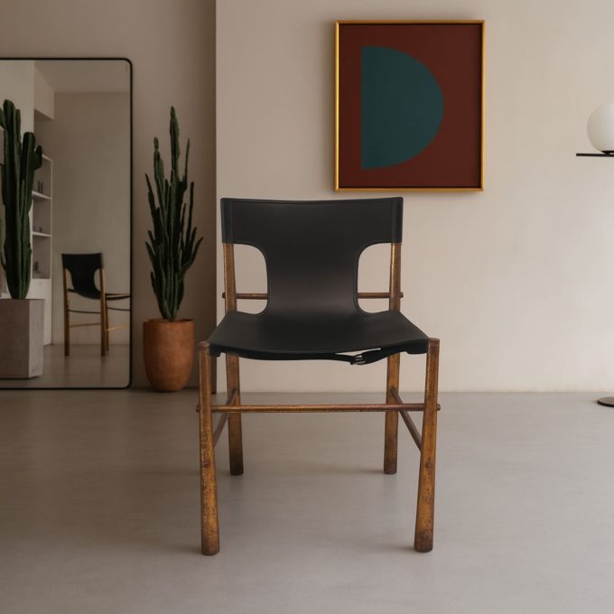 Sedia vintage italiana anni ’70 in ottone con seduta e schienale in pelle nera, vista frontale.